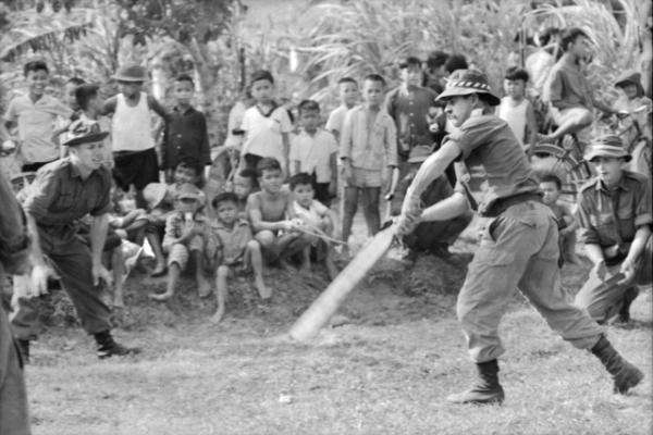Vietnam War: Private Frank Baker of the 5th Battalion, Royal Australian Regiment, hits out in front of villagers watching their first game of cricket near the Australian Task Force base at Nui Dat, South Vietnam