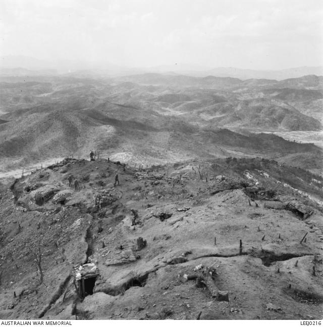 View of hills in Korea. The nearest hill, possibly Hill 317, is occupied by troops, possibly A Company of the 3rd Battalion, The Royal Australioan Regiment (3RAR), who have cut trenches and dugouts into it.