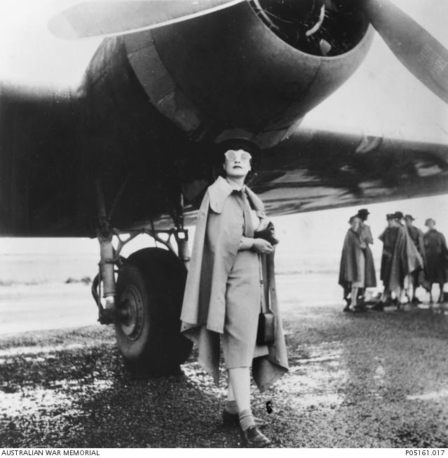 "The journalist Iris Dexter standing under the starboard engine of a Douglas C-47 aircraft."