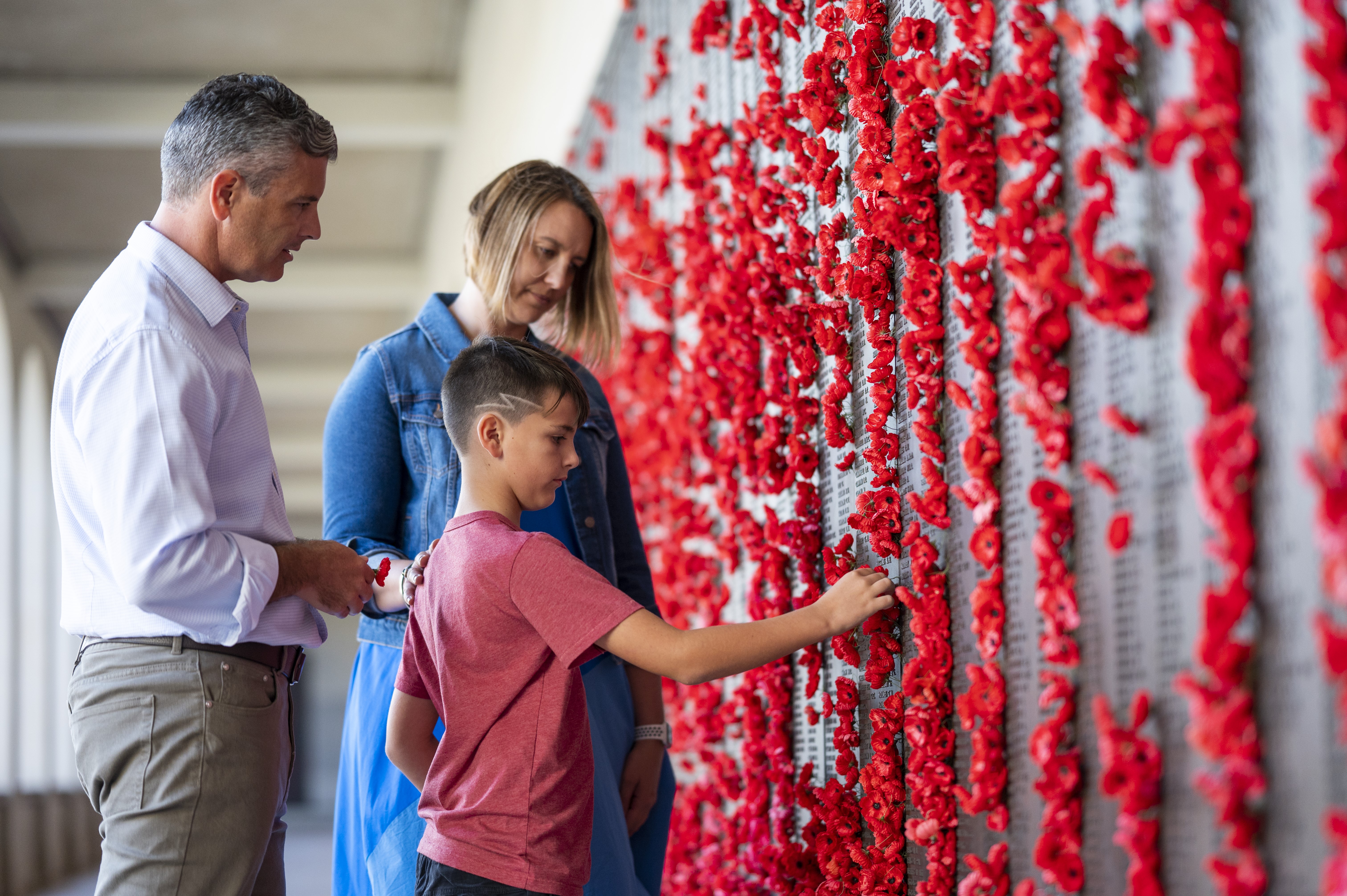 boy with family placing a poppy on the Roll of Honour