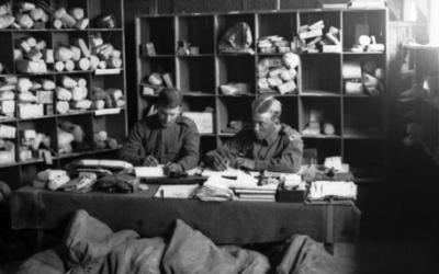 Two unidentified staff working at a table in the registration room at the Base Post Office at camp on the Suez Canal.