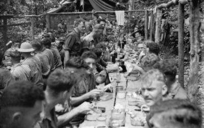 BOUGAINVILLE ISLAND. 1944-12-25. TROOPS OF THE 9TH INFANTRY BATTALION ENJOYING CHRISTMAS DINNER CONSISTING OF SOUP, TURKEY, HAM, ROAST POTATOES, PEAS, CHRISTMAS PUDDING, CUSTARD AND BEER.