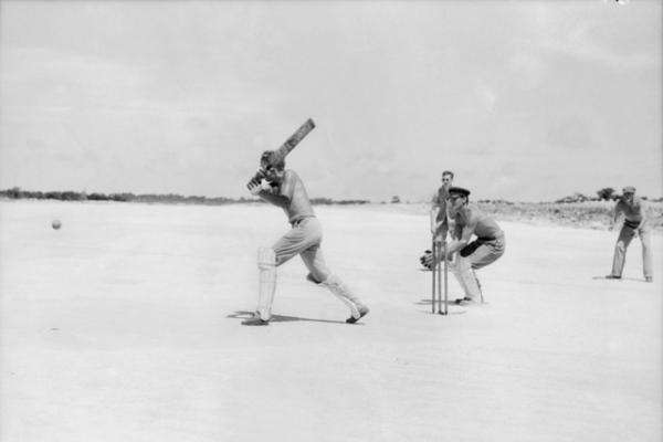 Aussies playing cricket on the end of a landing strip, Goodenough Island, New Guinea, December 1943.