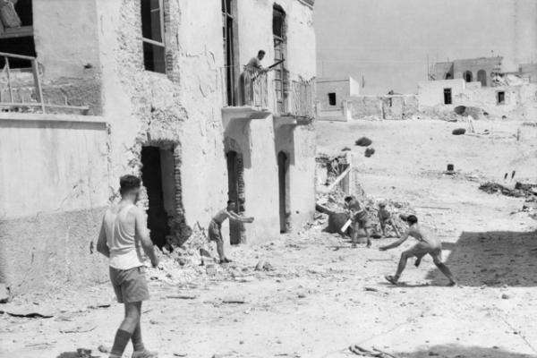 While one of their number kept a look-out above for enemy planes these Australians played a game of cricket in the ruins of a Tobruk street, September 1941.