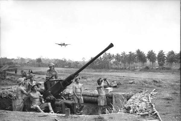 Milne Bay, Papua, September 1942: a Bofors gun position manned by the 2/9th Light Anti-Aircraft Battery, Royal Australian Artillery, at Gili-Gili airfield. In the background a Kittyhawk is about to land. AWM 026629