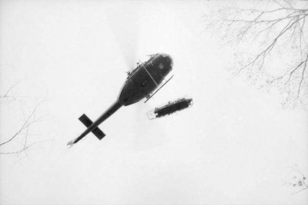 A wounded Australian soldier in a stretcher is winched from the ground into a helicopter, 1968