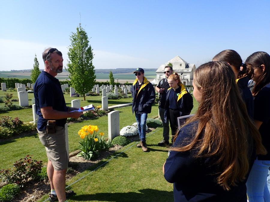 Teacher chaperone Mark Johnstone reads an account of a relative, Edward Radford, beside Radford’s grave at Villers–Bretonneux.