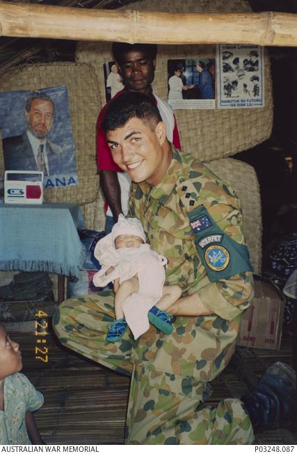 Ben holding his namesake, “Baby Benjamin”, in East Timor, 1999. (Wendy Sharpe, AWM P03248.087)