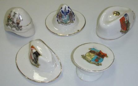 A collection of crested china military hats, including a pith helmet (REL23606 ); a ‘lemon squeezer’ hat (REL23607 ); Glengarry cap (REL23605); Australian slouch hat (REL23609) and peaked cap (REL23604).