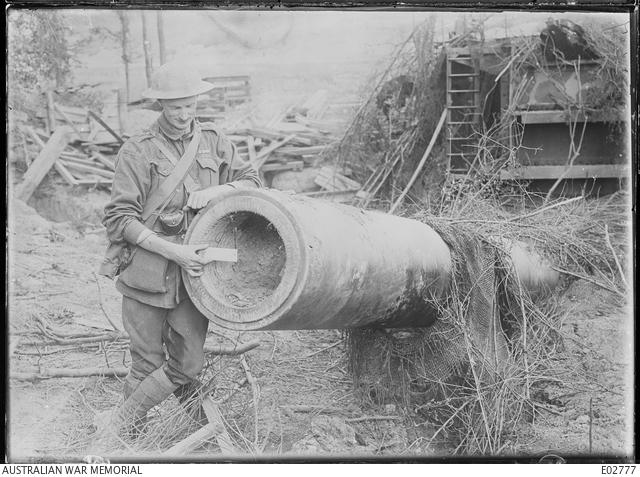 E02777 Lieutenant Cecil Clark, MM, MC, 3rd Battalion, holds a six-inch ruler to the muzzle of the gun.
