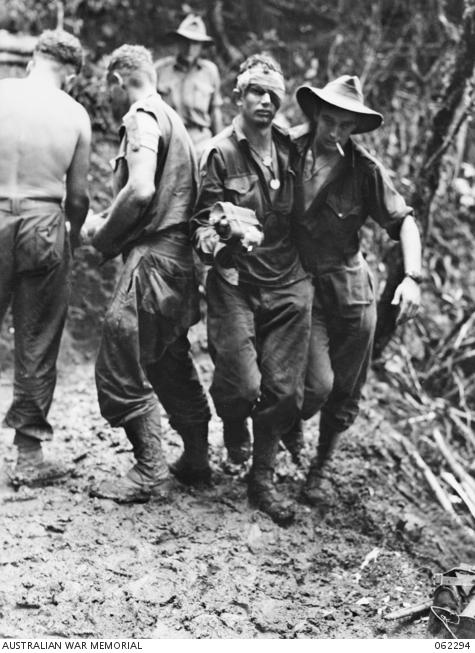 Private R. J. Rowe assists Corporal M. Hall, DCM, of the 2/16th Battalion to the regimental aid post after an attack on Shaggy Ridge.