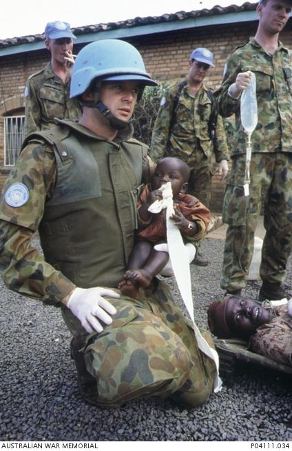 Lieutenant Robbie Lucas with a wounded child after the massacre (photo George Gittoes)