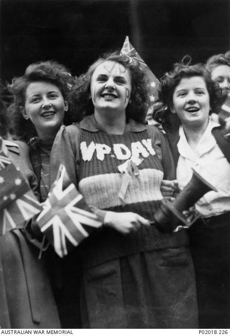 Lois Anne Martin, centre, wearing the vest she knitted for VP Day in Melbourne, 15 August 1945. AWM P02018.226