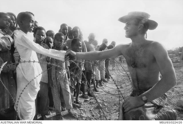 Sapper Keith Bawdan, of Kelmscott, WA, and Aitkenvale, Qld, greets one of the local children looking on behind the perimeter wire.