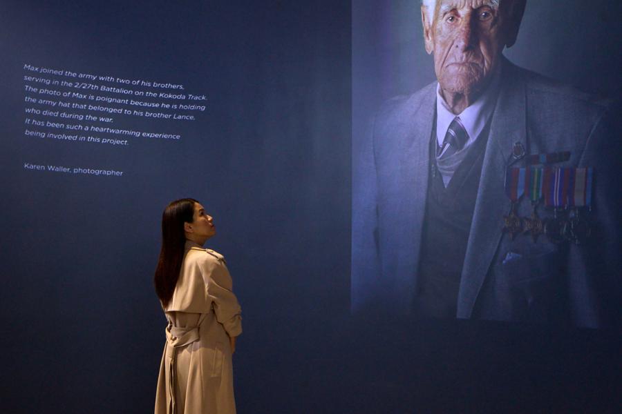 a woman gazes up at an image of a war veteran