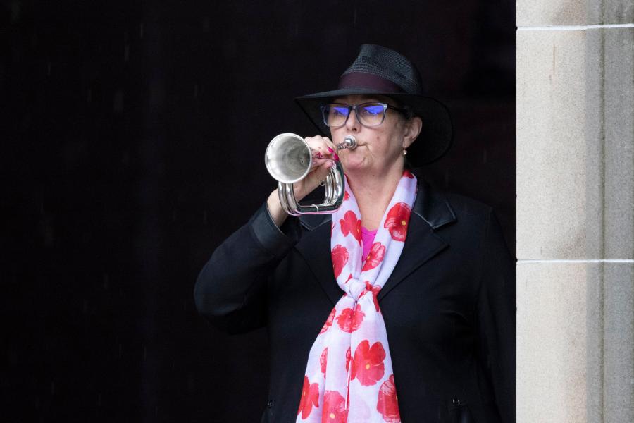 a woman plays the bugle at an anzac day ceremony