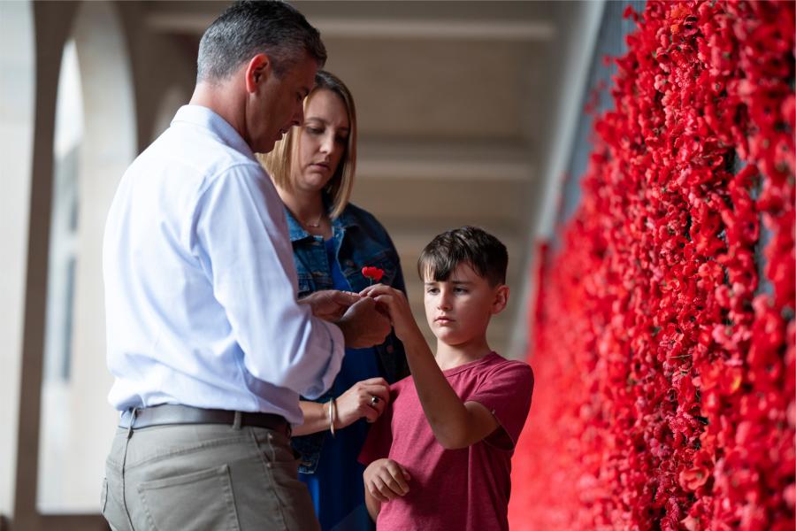 a family places a poppy on the Roll of Honour