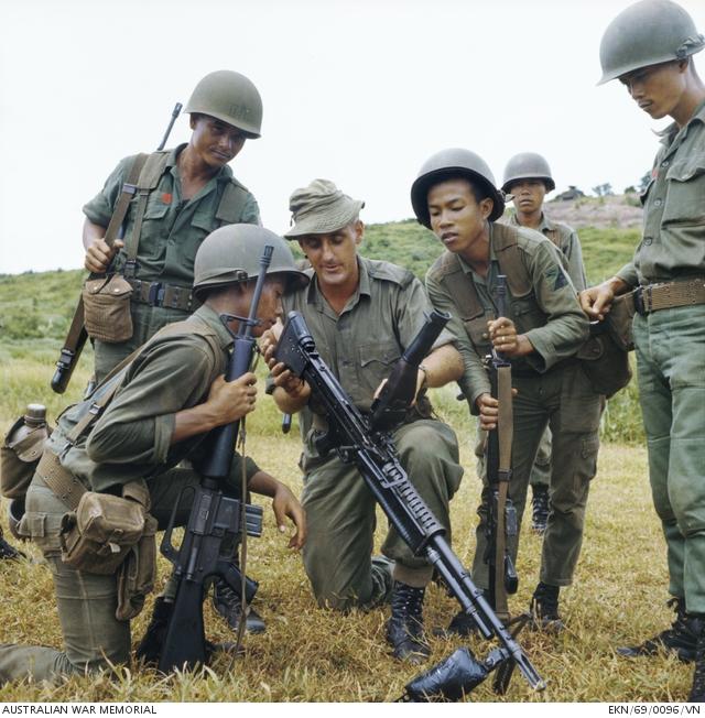 Horseshoe Hill, South Vietnam. 1969-09. Corporal (Cpl) David Waterston, 25, of Caulfield, Vic, shows Vietnamese soldiers of the 18th Division of the Army of the Republic of Vietnam (ARVN) how an M60 machine gun works. 