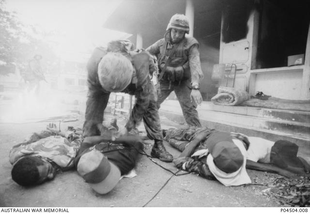 "Two unidentified Australian soldiers handcuff four alleged members of the Aitarak militia in a Dili street."