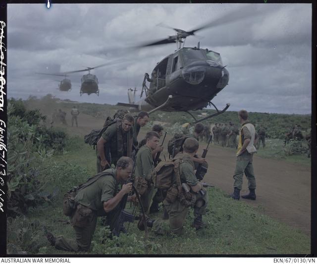 "Members of 5 Platoon, B Company, 7th Battalion, The Royal Australian Regiment (7RAR), just north of the village of Lang Phuoc Hai, beside Route 44 leading to Dat Do. United States Army Iroquois helicopters are landing to take them back to Nui Dat after completion of Operation Ulmarra"