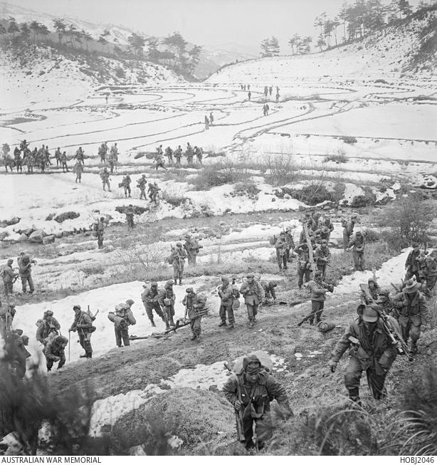 "Members of the 3rd Battalion, The Royal Australian Regiment (3RAR), walk carefully across a valley of snow covered rice paddies and up a hillside during an operation in Korea."
