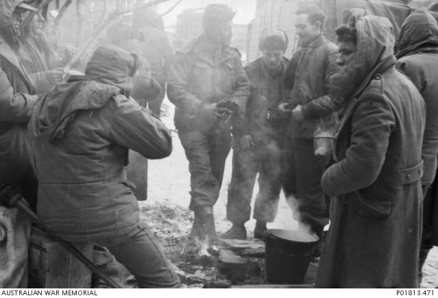 "Uijongbu, Korea, c. 1950-12-25. Rugged up in winter gear against the extreme cold of a Korean Christmas, members of the 3rd Battalion, The Royal Australian Regiment (3RAR), gather round a small campfire to try to get warm."