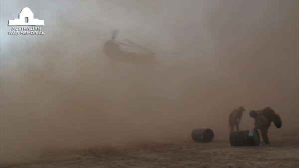 A United States Army Chinook helicopter lifting off and raising dust storm in the process