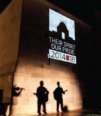 A photograph showing the new Centenary Logo projected on the exterior wall of the AWM