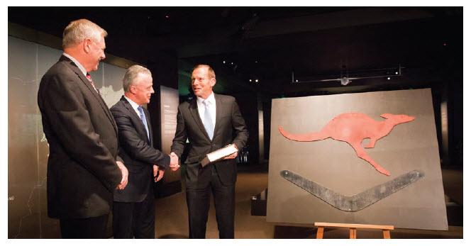a photograph of The Honourable Tony Abbott MP, Prime Minister of Australia, presents the boomerang and kangaroo sign that was mounted on the original Poppy's recreational centre in Tarin Kot, Afghansitan to Rear Admiral Ken Doolan AO RAN (Retd), Chairman and Dr Brendan Nelson, Director