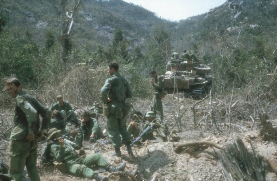 Major David Rankine, Officer Commanding C Company 8RAR (standing centre), and soldiers of company headquarters take stock after assessing the damage done by the B-52 strike. A large bomb crater is in the foreground.  Photo: Rod Simpson. 