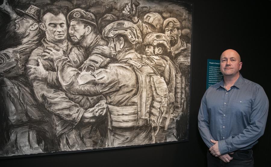 Rob Douma standing by his painting