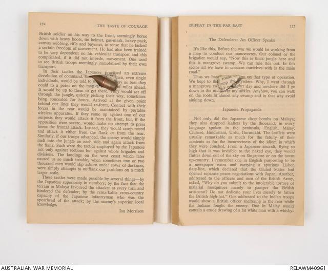 Paperback book edition of the 'The Taste of Courage: The War, 1939-1945' edited by Desmond Flower and James Reeves. The book is open to pages 174 and 175. A bullet has pierced the book from the rear and lodged in the pages. Damage continues until page 30. The spine is broken and separated at the open pages.