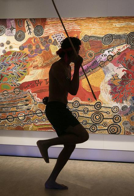 A dancer from the APY lands performs in front of the painting A dancer from the APY lands performs in front of the painting