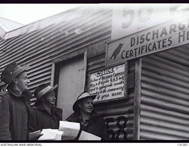 Three men standing in front of a discharge certificates notice