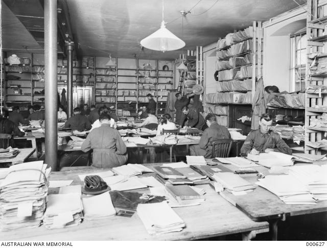 People working in an office surrounding by shelves and desks full of paper