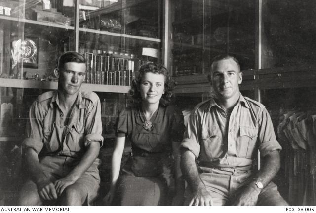 Informal portrait of VX4796 Private (Pte) Eric Clifton Eldridge, Headquarters, 17th Brigade, Australian Infantry, of Horsham, Vic (left); a shop girl (centre); and VX1113 Corporal (Cpl) Henry James Bailey Spencer (enlisted as Henry Bailey Spencer), 2/7th Battalion, of Alphington, Vic (right)