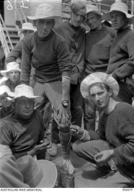 A group of soldiers on the deck of a ship looking at a just completed tattoo, the soldier "tattooist" and his tattooing equipment of electric needle, three batteries in series and a bottle of ink .