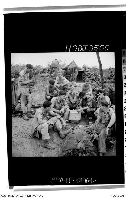 Korea. c. August 1952. Soldiers of C Company, 3rd Battalion, The Royal Australian Regiment (3RAR), listen to their new radio. A shirtless Desmond Parfitt is upper left of centre. 