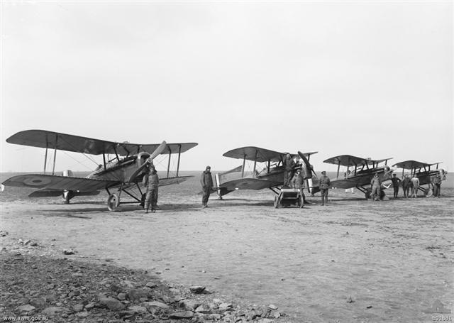 Four SE5 Biplanes and men of C Flight, No 2 Squadron, AFC lined up on a makeshift airfield in France, 25 March 1918.