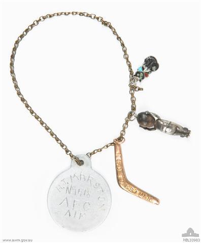 2am Henry J Marston's aluminium identity disc and three good luck charms affixed to a brass wrist chain. REL33983