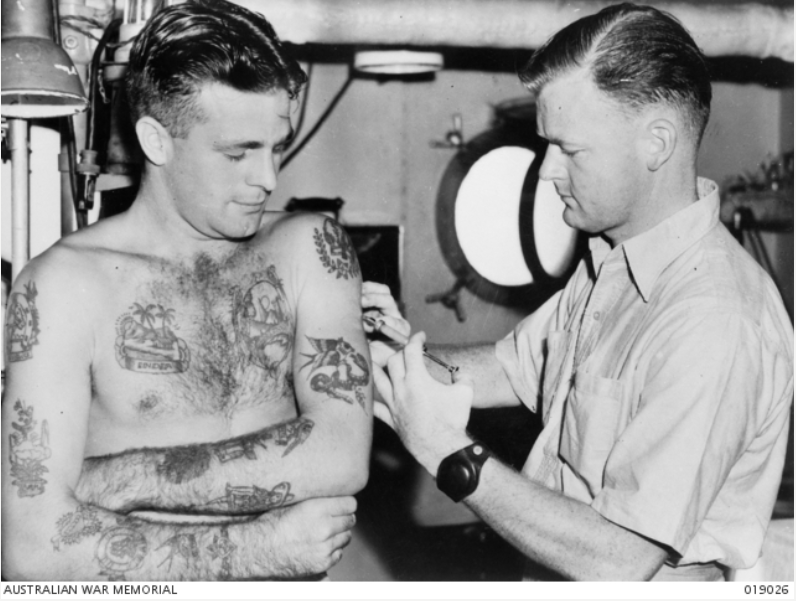 At sea in 1945, This photo shows  Able Seaman John Paterson ** receiving a needle from a doctor, rather than a tattooist! 