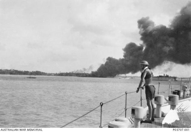 P03707.001 An unidentified sailor on board HMAS Platypus watches smoke billowing from MV Neptuna, destroyed during the first Japanese air raid on Darwin.